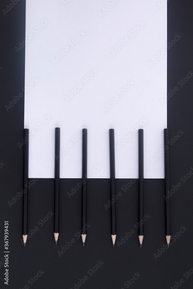 On a black table lie black pencils and white paper. Workplace. Flat lay. Business concept On a black table lie black pencils and white paper. Workplace. Flat lay. Business concept