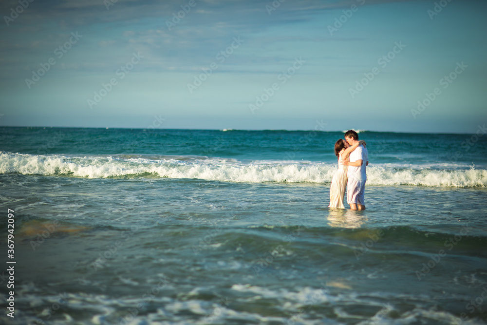couple in white clothes in water on beach. couple in white clothes in water on beach.