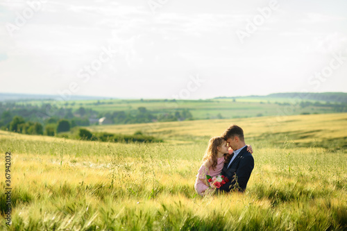 Father and daughter in a green wheat field.