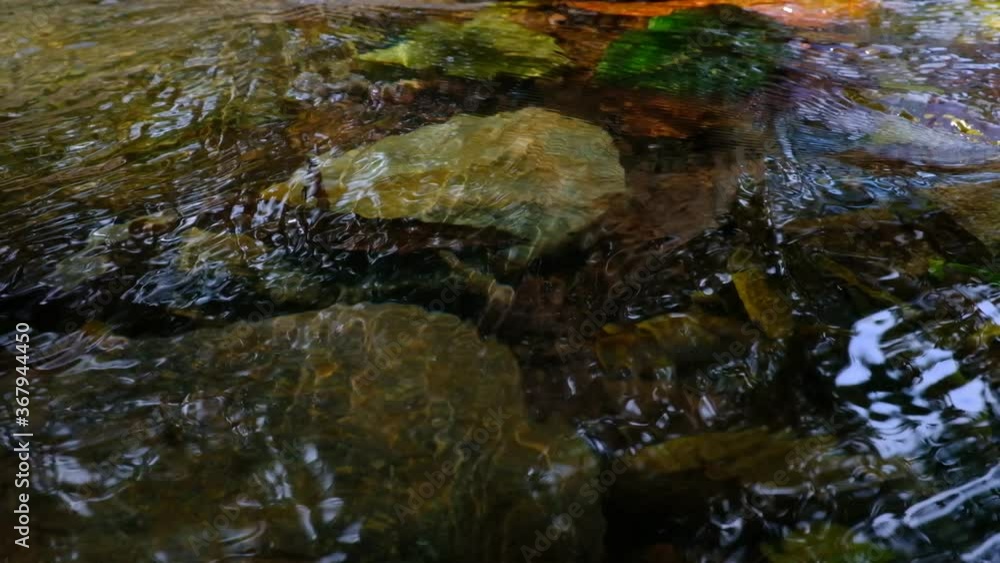 Closeup. The stream flows water with brown rocks. Closeup. The stream flows water with brown rocks.