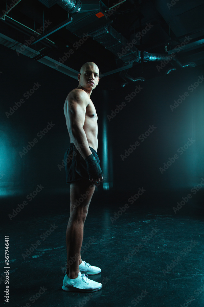 Calm shirtless man standing in shorts and training shoes