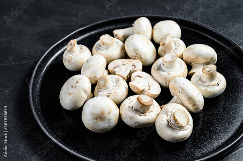 fresh mushrooms champignon on a plate. Black background. Top view