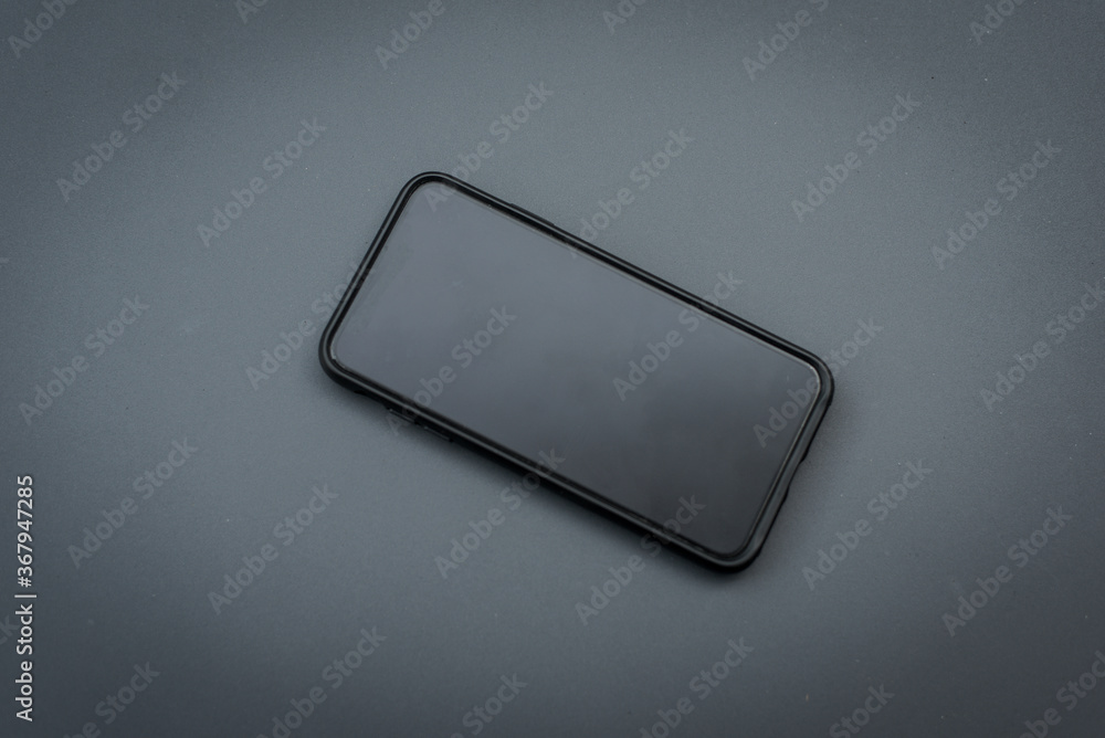 Black mobile device on a dark grey surface