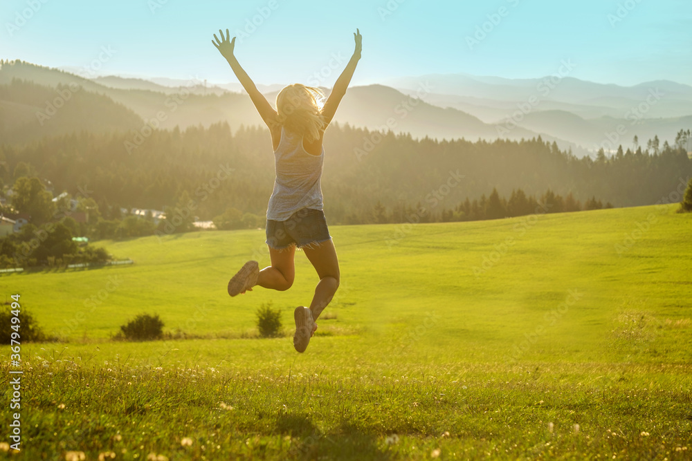 Happy woman with open arms stay on the peak of the mountain cliff edge under sunset light sky enjoying the success, freedom and bright future. Happy woman with open arms stay on the peak of the mountain cliff edge under sunset light sky enjoying the success, freedom and bright future.