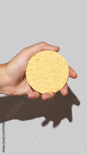 Woman hand hold remove makeup pad. Yellow cosmetology sponge for skincare routine. Unmakeup procedure. Self care. Healthy cosmetics product photo