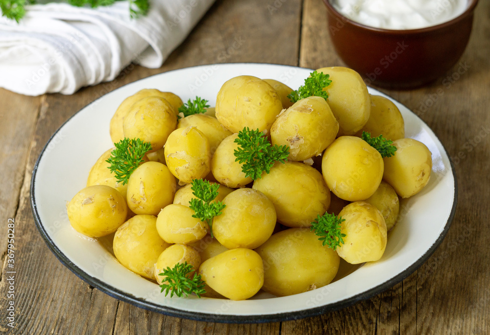 Young boiled potatoes with parsley on a rustic background
