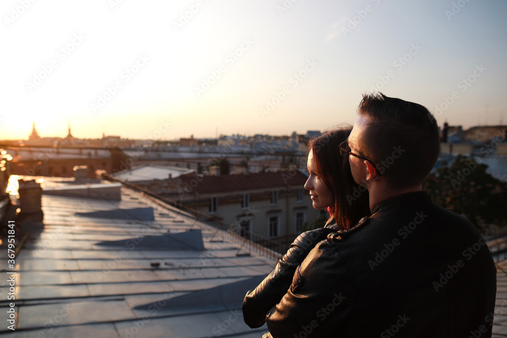 man and woman siting on rooftops historic center St. Petersburg and enjoying with  amazing sunset.