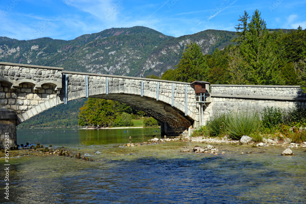 The old bridge over the lake against the background of mountains.
