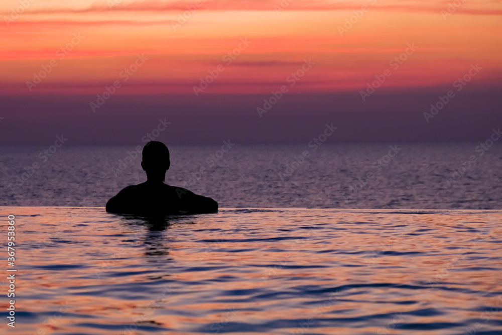 Swimming in sunset sunrise. Man swimming in infinity pool. Copy space banner. Hotel business, travel concept, travelling