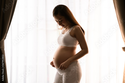 a beautiful woman pregnant in standing beside windows smiley happy and relax in bed room her with Pregnant Belly with hand touch on pregnant Belly Free Download a beautiful woman pregnant in standing beside windows smiley happy and relax in bed room her with Pregnant Belly with hand touch on pregnant Belly - GFXLoad