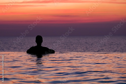 Swimming in sunset sunrise. Man swimming in infinity pool. Copy space banner. Hotel business  travel concept  travelling