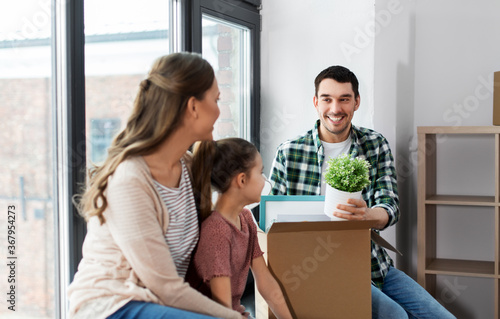 mortgage, family and real estate concept - happy mother, father and little daughter with stuff in boxes moving to new home