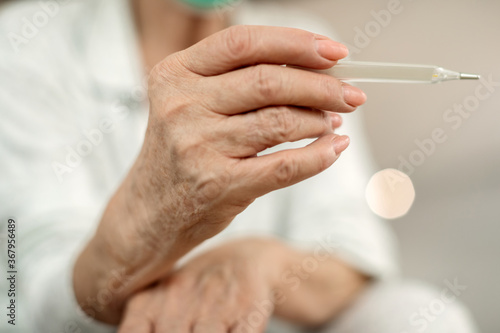 Close-up of mature woman measuring her temperature.
