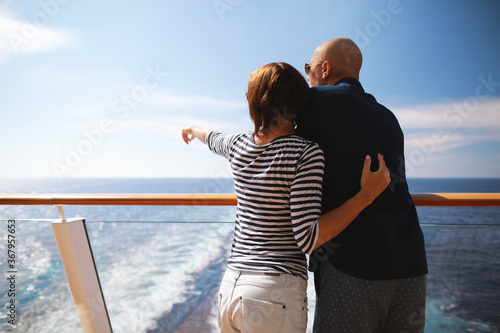caucasian man and brunette woman in sunglasses traveling together on cruise ship,standing on balcony and enjoying with beautiful view of Caribbean sea