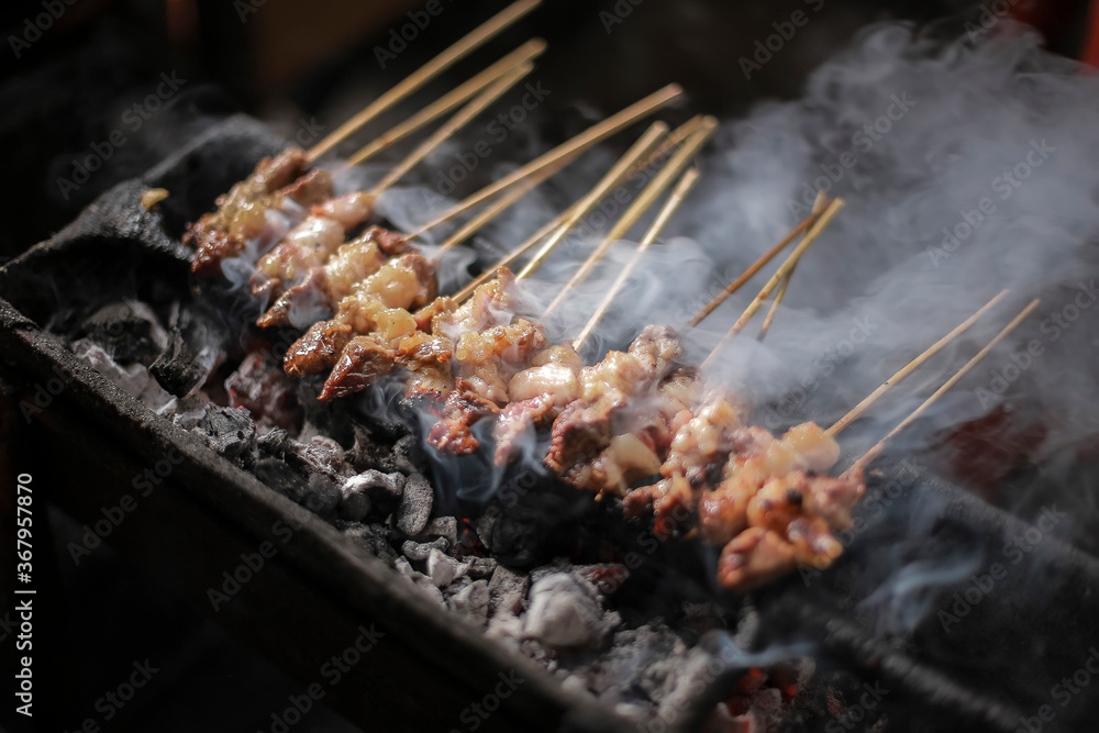 Satay goat (Sate kambing) satay lamb, lamb or meat goat satay in grilling place with smoke by people with yummy looking. traditional satay from java, Indonesia. Close Up Macro