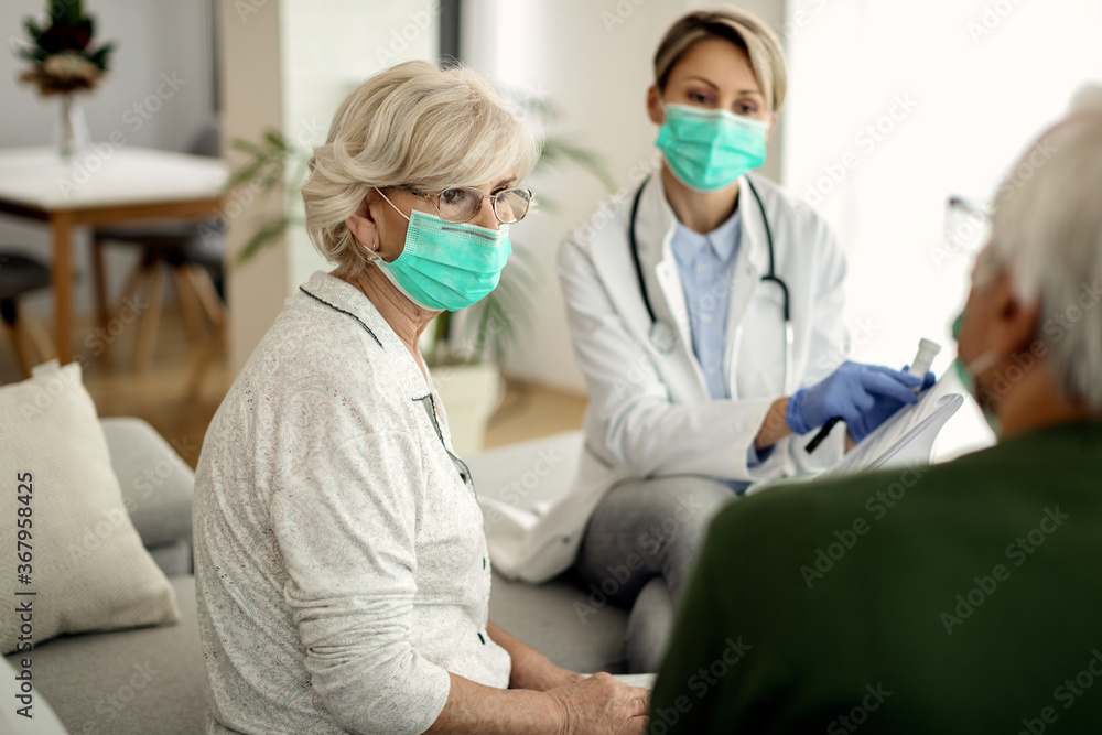 Senior woman with face mask talking to her husband during doctor's home visit. Senior woman with face mask talking to her husband during doctor's home visit.