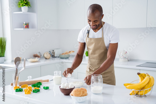 Portrait of his he nice attractive cheerful cheery guy confectioner making fresh bread egg pie hachapuri national culinary confectionery in modern light white interior house kitchen