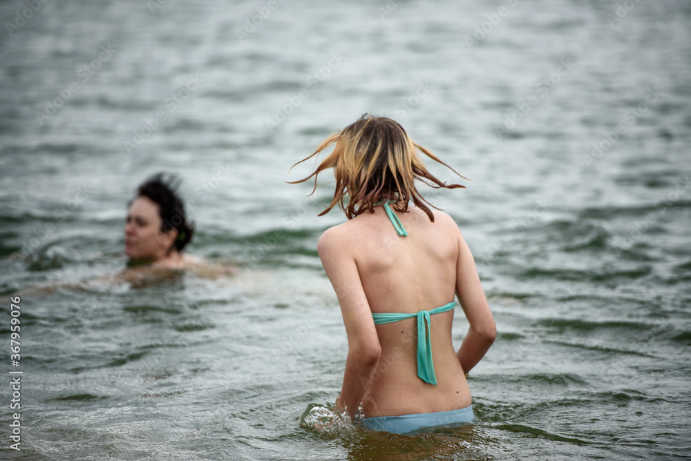 Two girls swim in the lake in the summer. The concept of a summer vacation.