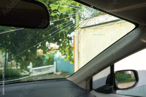 broken windshield with a lot of cracks and small glass pieces, damaged car