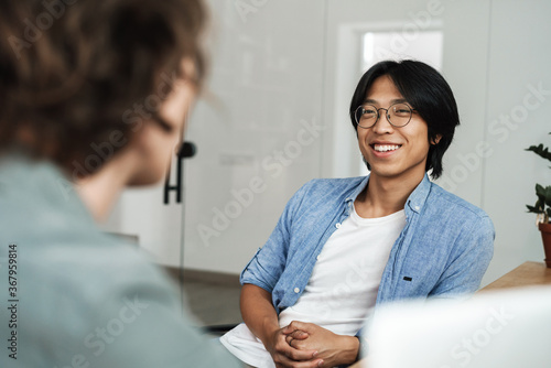 Image of multinational joyful colleagues discussing project and smiling