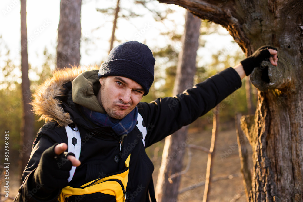 Funny young man leaning in the tree thunk and grimacing, trying to amuse you  Stock Photo | Adobe Stock