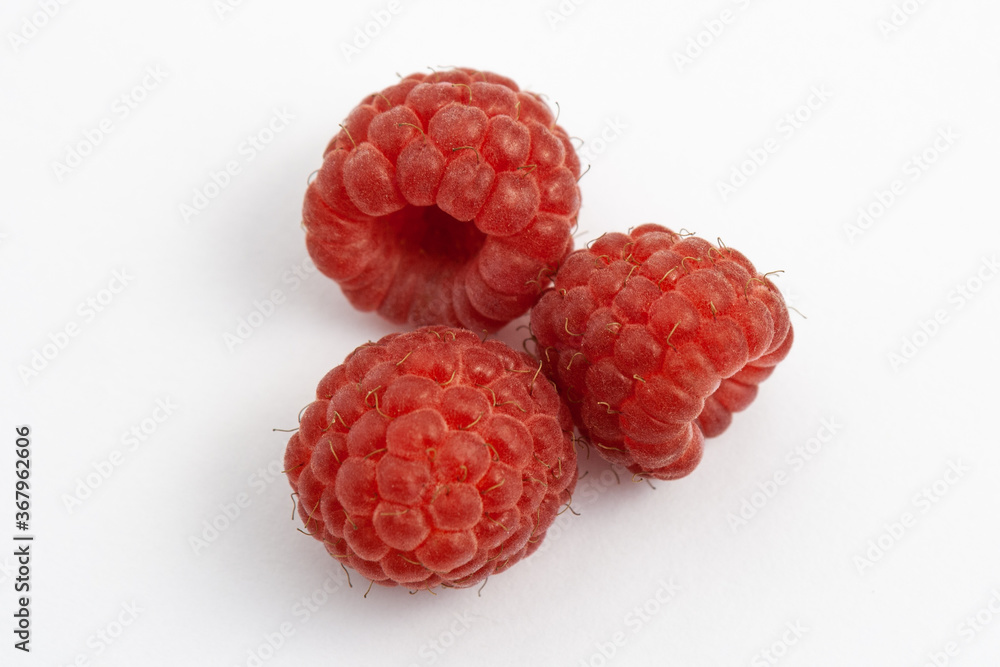 Three ripe raspberries isolated on a white background close-up. Fresh raspberries without sheets on the table. Macro shooting. Healthy and wholesome food concept Three ripe raspberries isolated on a white background close-up. Fresh raspberries without sheets on the table. Macro shooting. Healthy and wholesome food concept