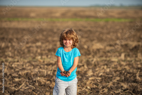 Kids farmer. American child on farm. Soil and ground concept. Textured fertile soil as background. Gardening season.