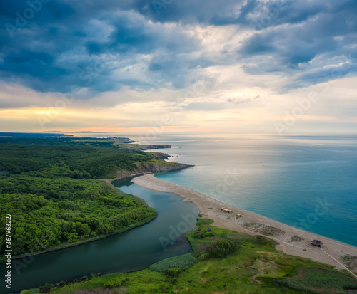 An empty wild beach, surrounded by rocks and green thick forests. Aerial view with beautiful, wild beach at the Black Sea coast and the estuary of Veleka river, Bulgaria.