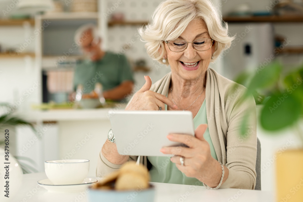 Happy senior woman making video call over touchpad at home. Happy senior woman making video call over touchpad at home.
