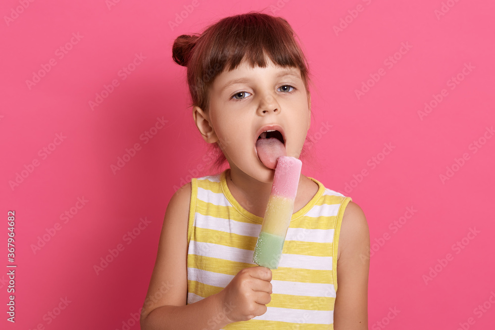 Little girl eating fruit ice cream widely opened mouth, looking at