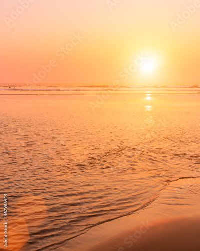 A colorful sunset or sunrise on the seaside with a sandy beach with impurities of volcanic ash. Mandrem, Goa, India. photo