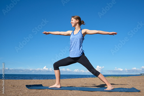 Young slim girl doing yoga on the beach on a sunny morning