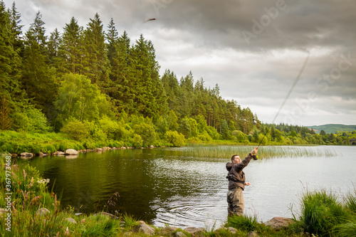 An action shot of a fly fisherman casting a pike fly on Loch Stroan, Scotland photo