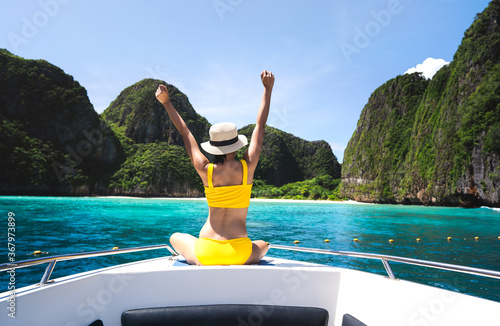 Rear view of adult traveling woman relax arm stretch on the sailing boat with summer island and sea
