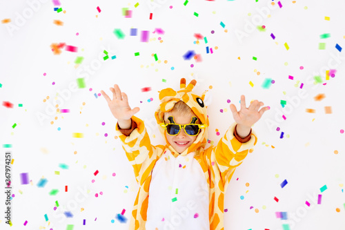 little boy in a fun bright giraffe costume on a white isolated background with confetti, children's birthday, place for text