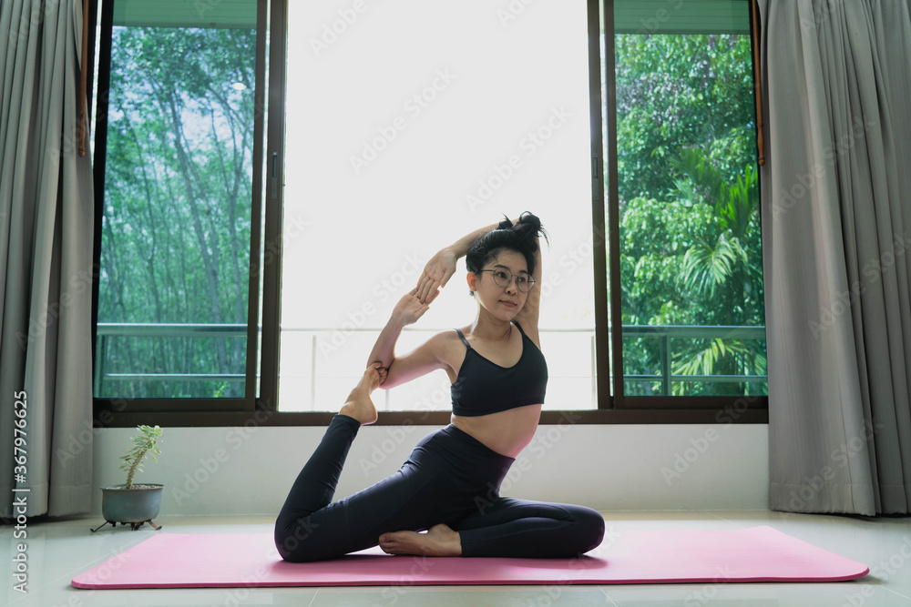 fitness, people and healthy lifestyle concept - Woman wearing sportswear practicing mermaid asana at home for health and a firmer body.Eka pada rajakapotasana pose