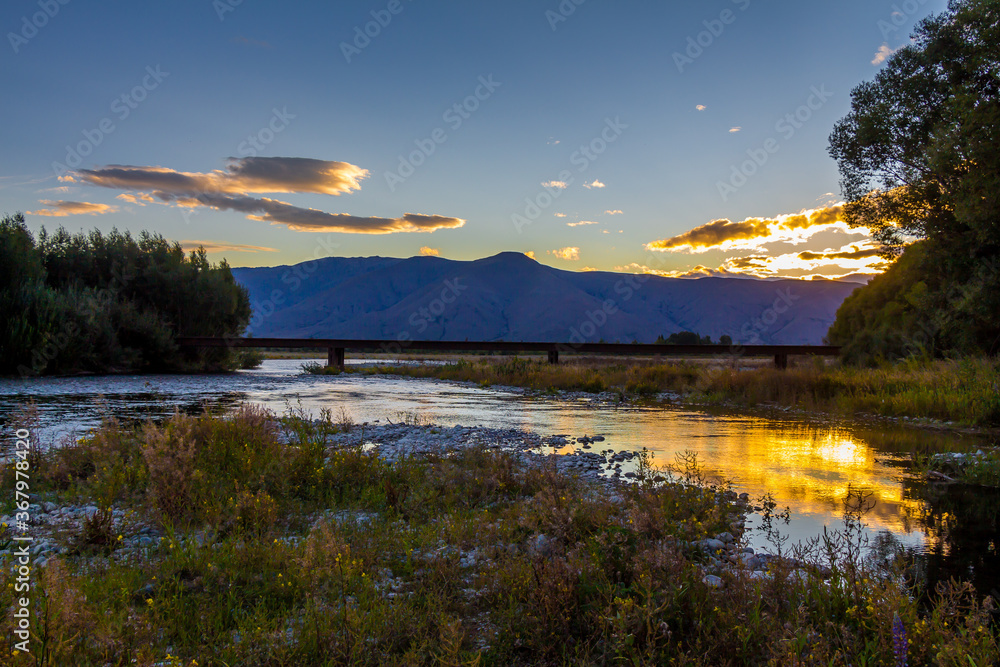 Sunset on the Tekapo River, with mountains in the background in summer, South Island, New Zealand