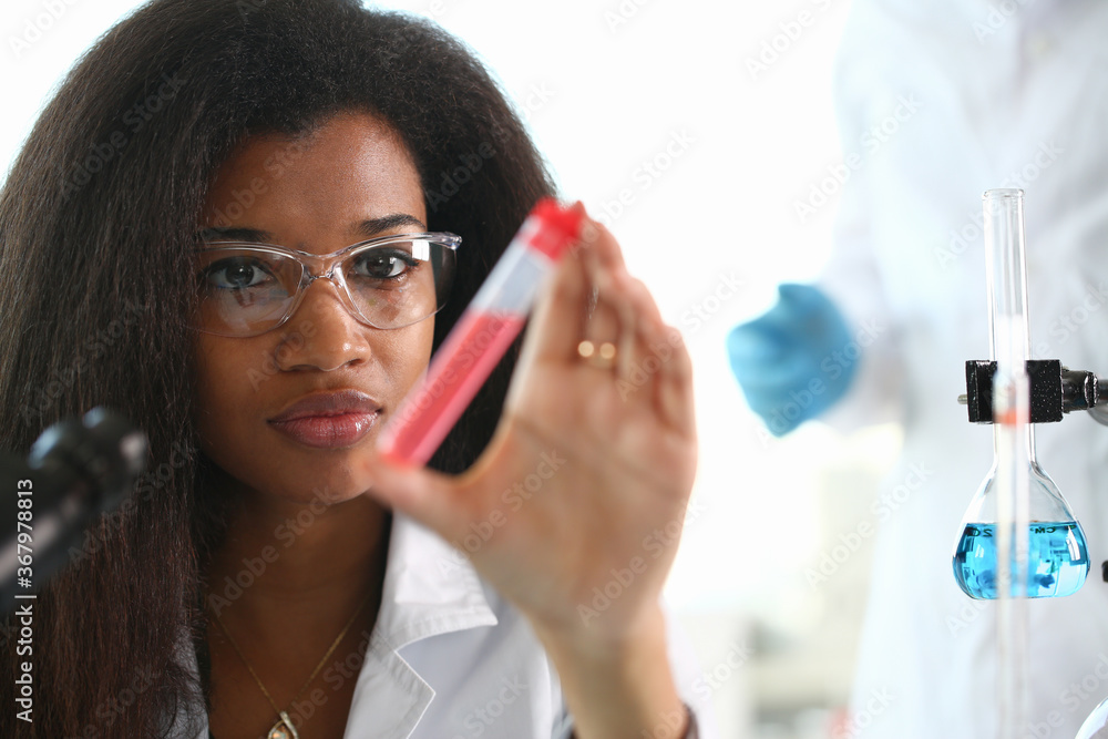 A female chemist holds test tube of glass in his hand overflows liquid solution potassium permanganate conducts an analysis reaction takes various versions reagents using chemical manufacturing. - obrazy, fototapety, plakaty 