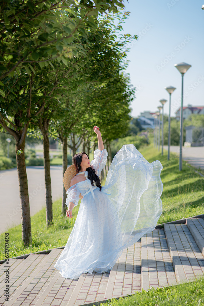 Pregnant woman posing in a blue dress on a background of green trees. Pregnant woman posing in a blue dress on a background of green trees.