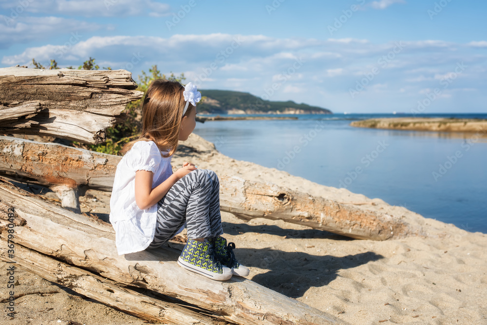 A little girl enjoys the sunny warm day at the sandy beach