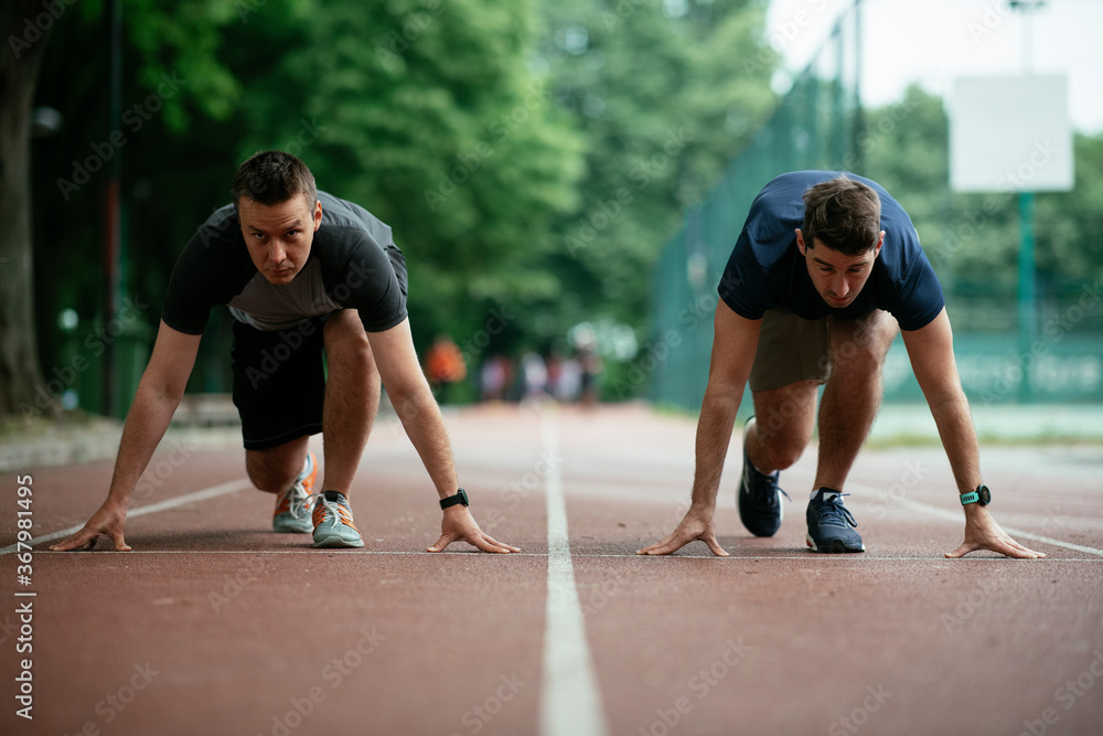 Athlete men in sportswear in start position for running. Close up.