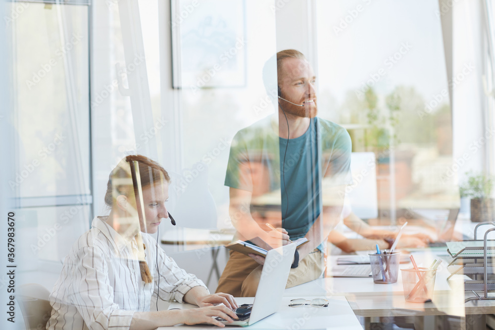 Group of office workers working together at office behind the glass wall Group of office workers working together at office behind the glass wall