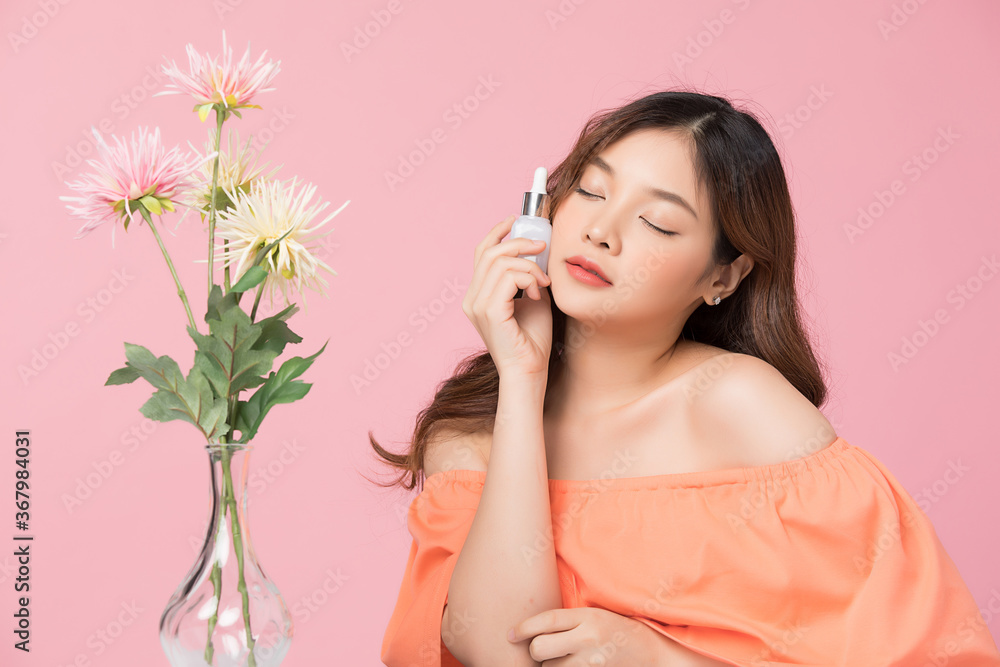 Beautiful young woman model with flowers posing, isolated on pink studio background Beautiful young woman model with flowers posing, isolated on pink studio background