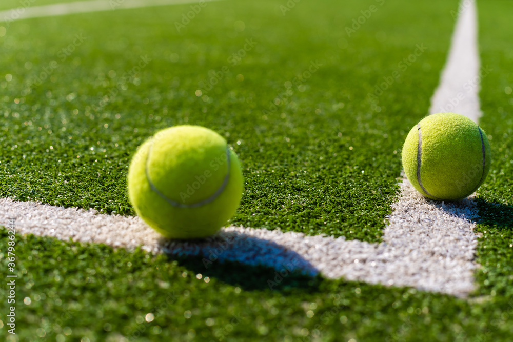 Green ball falling on floor nearly white lines of outdoor tennis court in public park