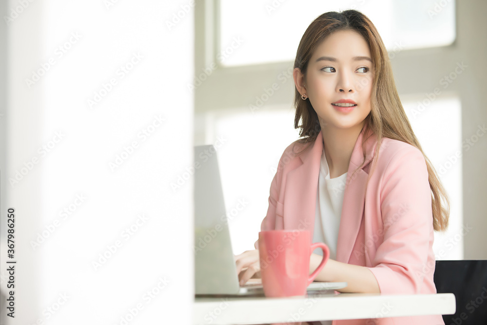 Young beautiful business woman working in office with notebook computer and coffee cup on the desk Young beautiful business woman working in office with notebook computer and coffee cup on the desk