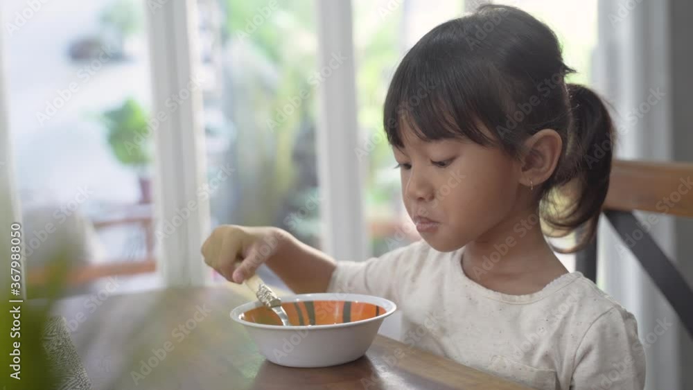 cute asian toddler having breakfast by herself at home in the morning cute asian toddler having breakfast by herself at home in the morning