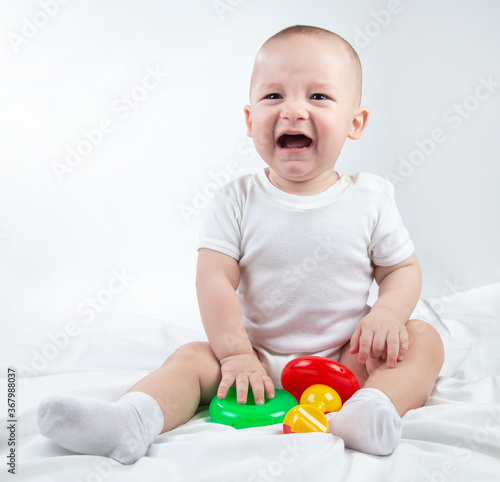 Bild auf Leinwand Photo of a crying nine-month-old baby with bright toys