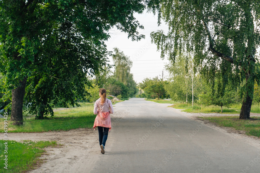 Girl walks along a road village with trees on her back Girl walks along a road village with trees on her back