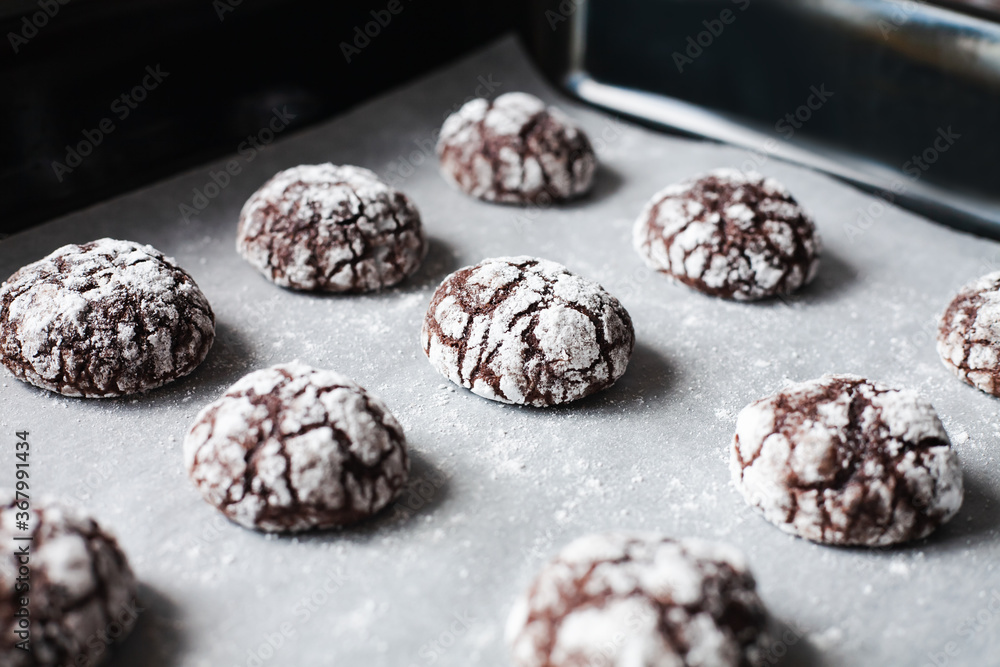 Chocolate cookies with powdered sugar on baking tray. Close-up. Chocolate cookies with powdered sugar on baking tray. Close-up.