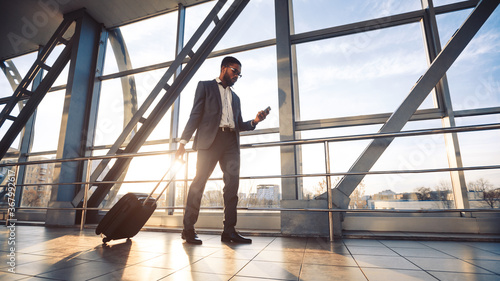 Man Using Phone And Business App Walking To Airport Gate